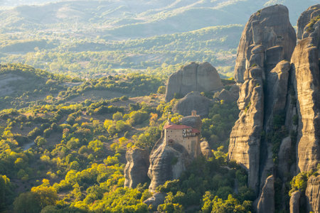 Greece. Sunny summer evening in the Kalambaka valley. Stone gazebo and small monastery with red roofs on the rockの写真素材