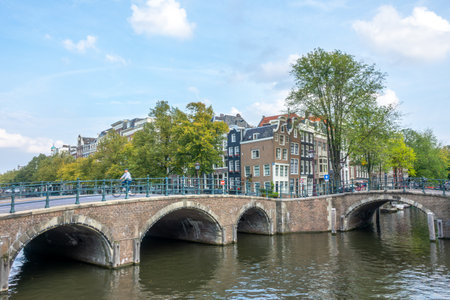 Netherlands. Summer day. Typical Dutch houses on the Amsterdam embankment at the confluence of the canals. Light clouds in the blue skyの写真素材