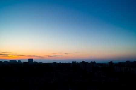 Five minutes before sunrise over the city. Almost clear sky with a light area above the horizon. Silhouettes of buildings in backlightの写真素材