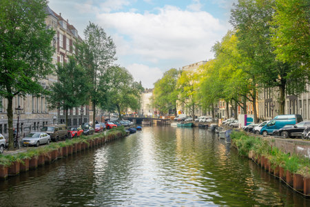 Netherlands. A summer day on a canal in the center of Amsterdam. Many cars are parked on the embankments. Several boats are moored on the waterの写真素材