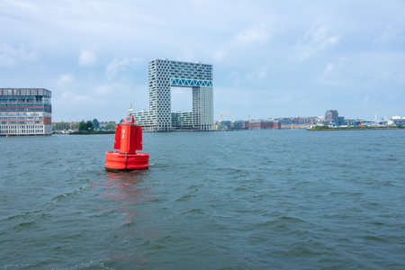 Netherlands. Summer day in Amsterdam. Buoy on the Amstel River and an office building on the bankの写真素材