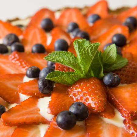 Homemade cheesecake decorated with organic strawberries, blueberries and fresh mint and cream. Nice pie for a holiday celebration or any birthday party.の写真素材