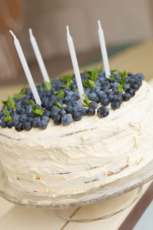 A big white birthday cake with fresh organic blueberries and mint and white candles on the top. Party cake. Homemade cake with berries. Cake decorの写真素材