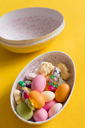 Easter egg box with candy and chocolate, scandinavian tradition. close up on yellow backgorund.  big...