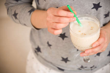 Young woman with a big glass of healthy smoothie served with a straw and oats. Hands holding milkshake. Stars background. Dairy snack or breakfast. Horizontal view.の写真素材