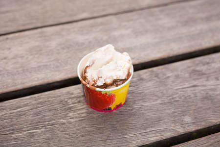 A cup of soft ice cream on the wooden background. Summer dessert on the wooden table in a cafe...