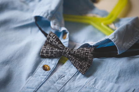 Close-up of blue shirt with a bow tie on a hanger. Black bow tie with scientific symbols. Clothes. Special occasion suit. Clothes on a hanger.の写真素材