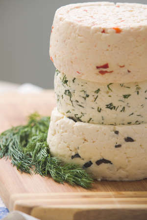 Variety of home made cheese  and herbs on a wooden board. brined curd white cheese on the table.の写真素材