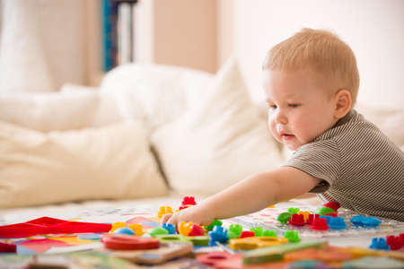 Cute preschooler child boy plays with mosaic at home. A blond little toddler playing in kid's room....