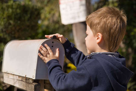School boy opening a post box and checking mail. Kid waiting for a letter, checking correspondence...