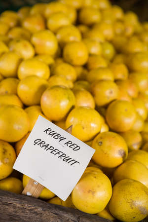 Pile of orange ruby grapefruit on the wooden table in the market. Fruit harvest. Local farm market. Healthy fruit. Vitamins.の写真素材