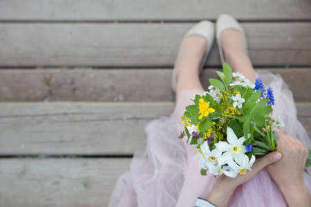 Top view on woman holding beautiful bunch of spring flowers. Girl with bouquet of daffodils, apple tree flowers and other garden flowers. Summer and spring concept. Selective focus.の写真素材