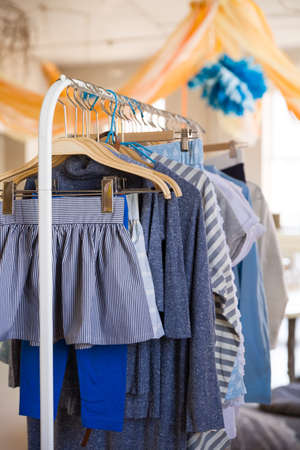 Hangers with clothes for kids on it. Rack with girl's clothes in blue color in a shopの写真素材