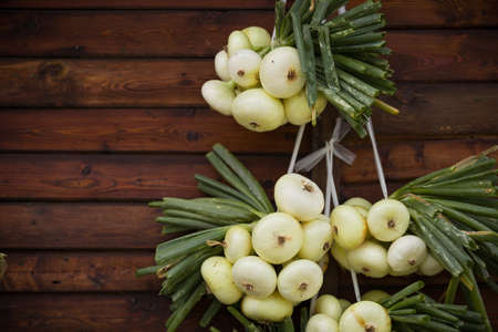 Organic white onions and shallots hanging on wooden background. Harvest. Garden. Health and lifestyle concept.の写真素材
