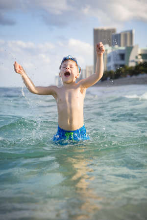 Happy kid boy running on the ocean beach. Exciting child having fun on the beach. Vacations by the sea. Outdoor activities with children. Summer swimming.の写真素材