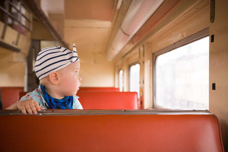 Cute little toddler boy sitting inside the train. Child traveling by railway. young traveler. Vacations. Indoors.の写真素材