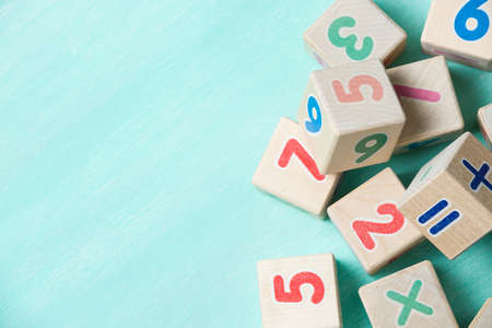 Wooden cubes with numbers on a turquoise wooden background.