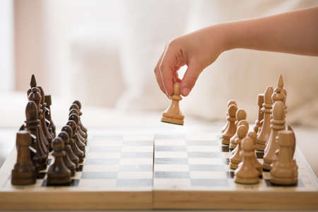 Closeup of Boy's hand holding chess figure while playing chess in the room. Little clever child...