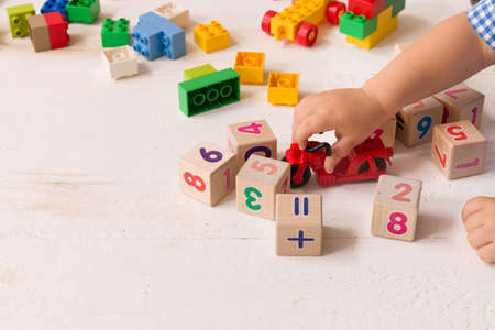 Close up of child's hands playing with colorful plastic bricks and red motocicle at the table. Toddler having fun and building out of bright constructor bricks. Early learning.   Developing toysの写真素材
