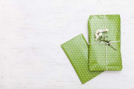 Top view on nice wrapped gift with flowers on white wooden background. Present for birthday, Christmas and any other celebration. Holidays conceptの写真素材