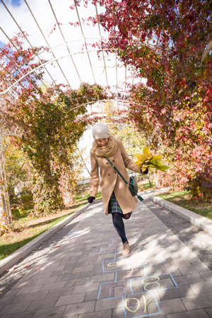 Happy young woman dancing in the park in an autumn sunny day. Girl enjoying walking in the park and holding yellow leaves. Woman with bunch of leaves running outdoors.の写真素材