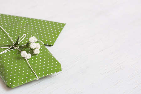 Top view on nice wrapped gift with flowers on white wooden background. Present for birthday,...