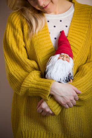 Smiling woman holding small Santa Claus. Father Christmas toy in girl's hands. Holiday season and...