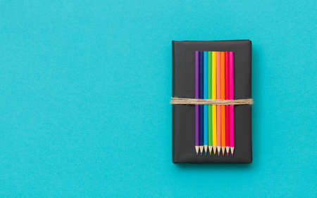 Colorful school and office supplies  - pencils and ruler on black book and blue background. Top view...