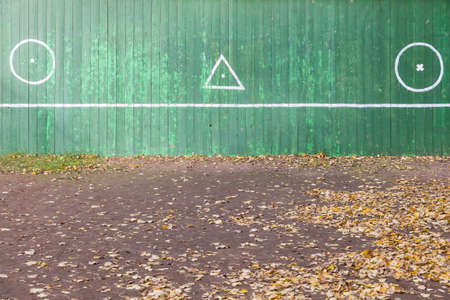 Old tennis court with wooden green wall and geometric signs on it. Outdoors sport.の写真素材