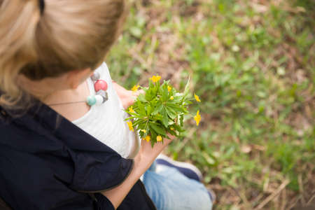 Young woman holding a bouquet of wild flowers.Top view. Outdoors. Girl with summer flowers..
