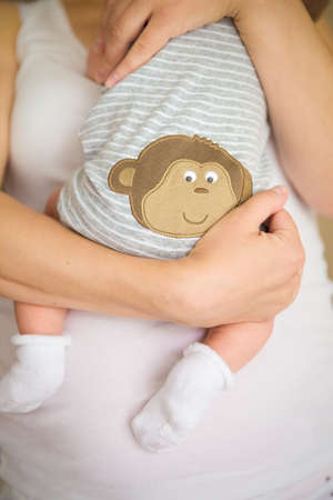 Close-up of tiny baby in socks in the hands of his mother. Young mom hugging her newborn child. Motherhood and childhood. New life.の写真素材