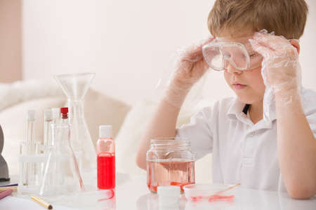 Cute kid boy in glasses making science experiments. Little child working with liquids.の写真素材
