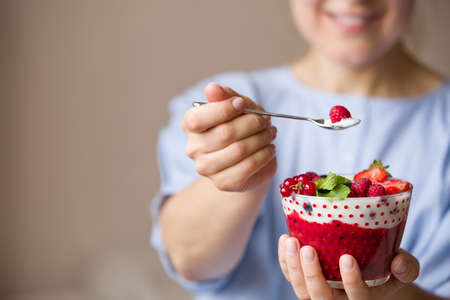 Woman  holding smoothie bawl with organic yogurt, berries and mint. Homemade yogurt in girl's hands served with raspberry, strawberry and blueberry. Breakfast. snack. Healthy eating, lifestyle conceptの写真素材