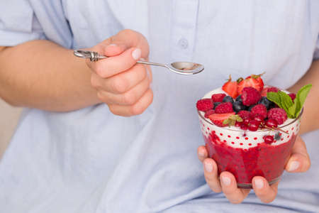 Woman  holding smoothie bawl with organic yogurt, berries and mint. Homemade yogurt in girl's hands...