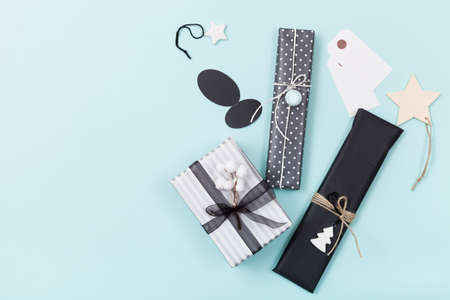 Top view on nice Christmas gifts packed in black and striped paper and decorated with stars on light...