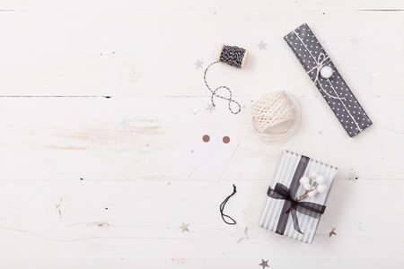 Top view on hands packing nice Christmas gifts. Presents, decor elements on wooden background. Holidays and winter concept.の写真素材