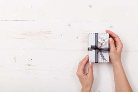 Top view on woman's hands holding nice Christmas gift packed in striped paper with ribbon. Present. Celebration and holiday seasonの写真素材