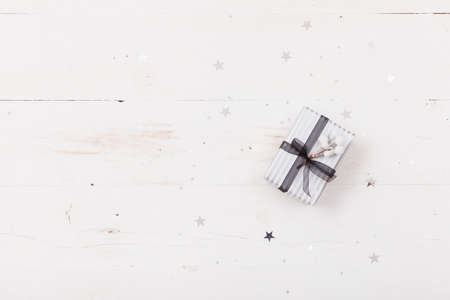 Top view on nice Christmas gift packed in striped paper  on wooden background. Presents and decor elements. Holidays and winter concept.の写真素材