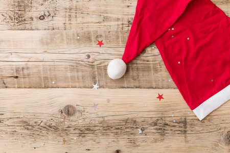 Top view on Santa's hat on retro wooden background with shiny stars. Christmas, winter and holidays season concept.の写真素材
