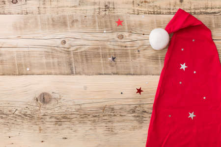 Top view on Santa's hat on retro wooden background with shiny stars. Christmas, winter and holidays season concept.の写真素材