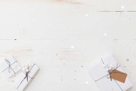 Top view on nice Christmas gifts wrapped in white gift paper, Christmas tree decorations on white wooden background with sparkling stars. New Year, holidays and celebration conceptの写真素材