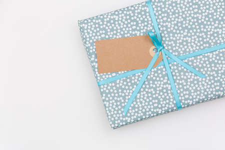 Top view on a wrapped in paper gift for birthday, Christmas, or other celebration on white wooden background. Gift box with tag and ribbon. Birthday present. Wrapping gift idea.の写真素材