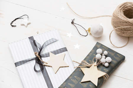 Nice Christmas gifts packed in black and striped paper and decorated with stars on wooden background. Presents and decor elements. Holidays and winter concept.の写真素材