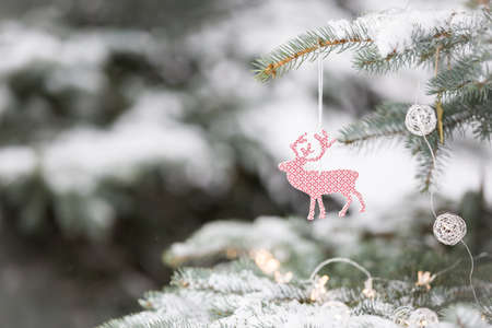 Nice decorations on a Christmas tree with snow outdoors. Celebration, winter and holidays conceptの写真素材
