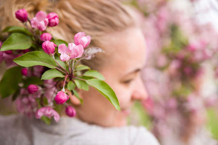 Portrait of a young smiling woman in the apple trees' blossom. Blooming apple tree. Spring time with...