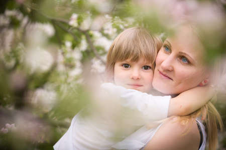 Portrait of happy family enjoying sunny day in the park. Young woman hugging cute toddler boy. Mother and son. outdoors. Lifestyle conceptの写真素材