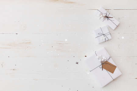 Top view on nice Christmas gifts wrapped in white gift paper, Christmas tree decorations on white wooden background with sparkling stars. New Year, holidays and celebration conceptの写真素材