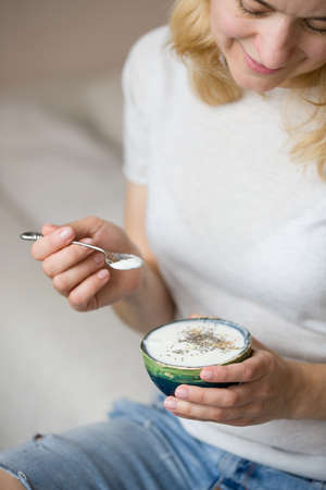 Closeup of woman's hands holding cup with homemade organic vanilla yogurt with chia seeds. Breakfast, snack. Healthy eating and lifestyle conceptの写真素材