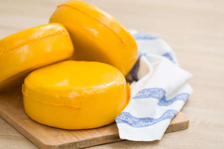 Three big organic cheese heads in yellow vacuum package laying on top of each other in the farm kitchen.  Food conceptの写真素材