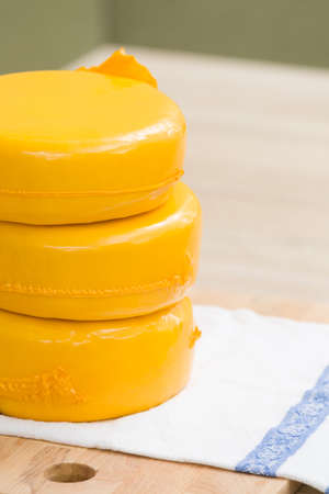 Three big organic cheese heads in yellow vacuum package laying on top of each other in the farm kitchen.  Food conceptの写真素材